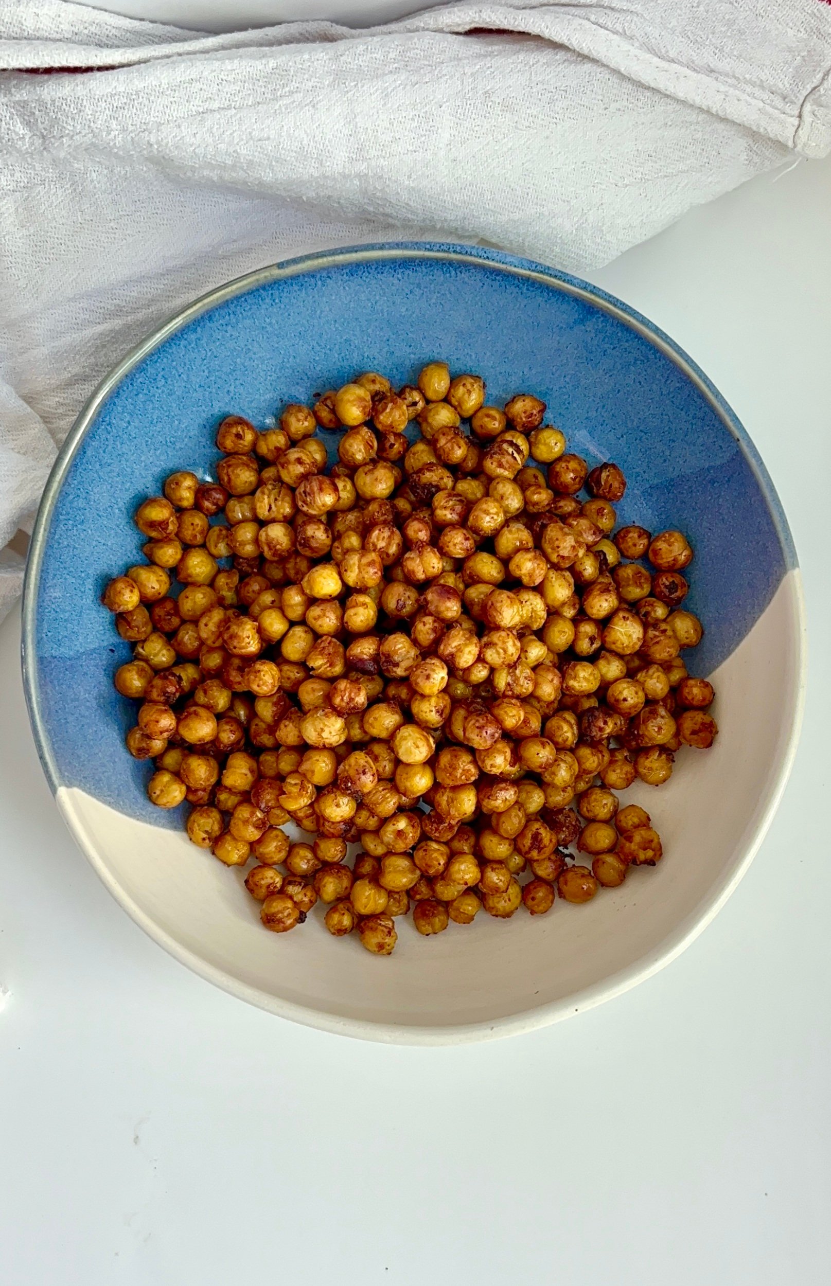 Blue and white bowl on a white background with roasted chickpeas inside