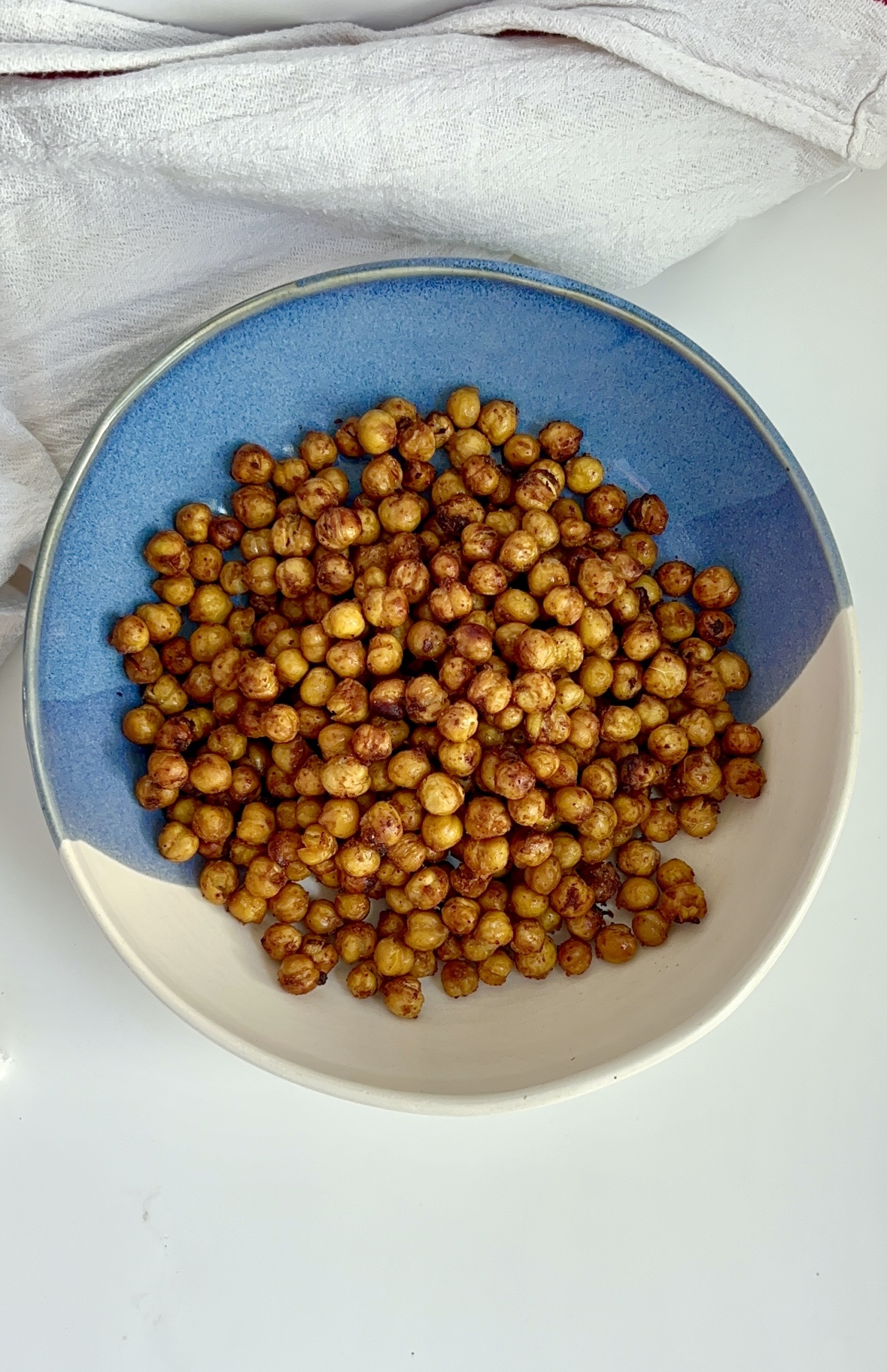 Blue and white bowl on a white background with roasted chickpeas inside