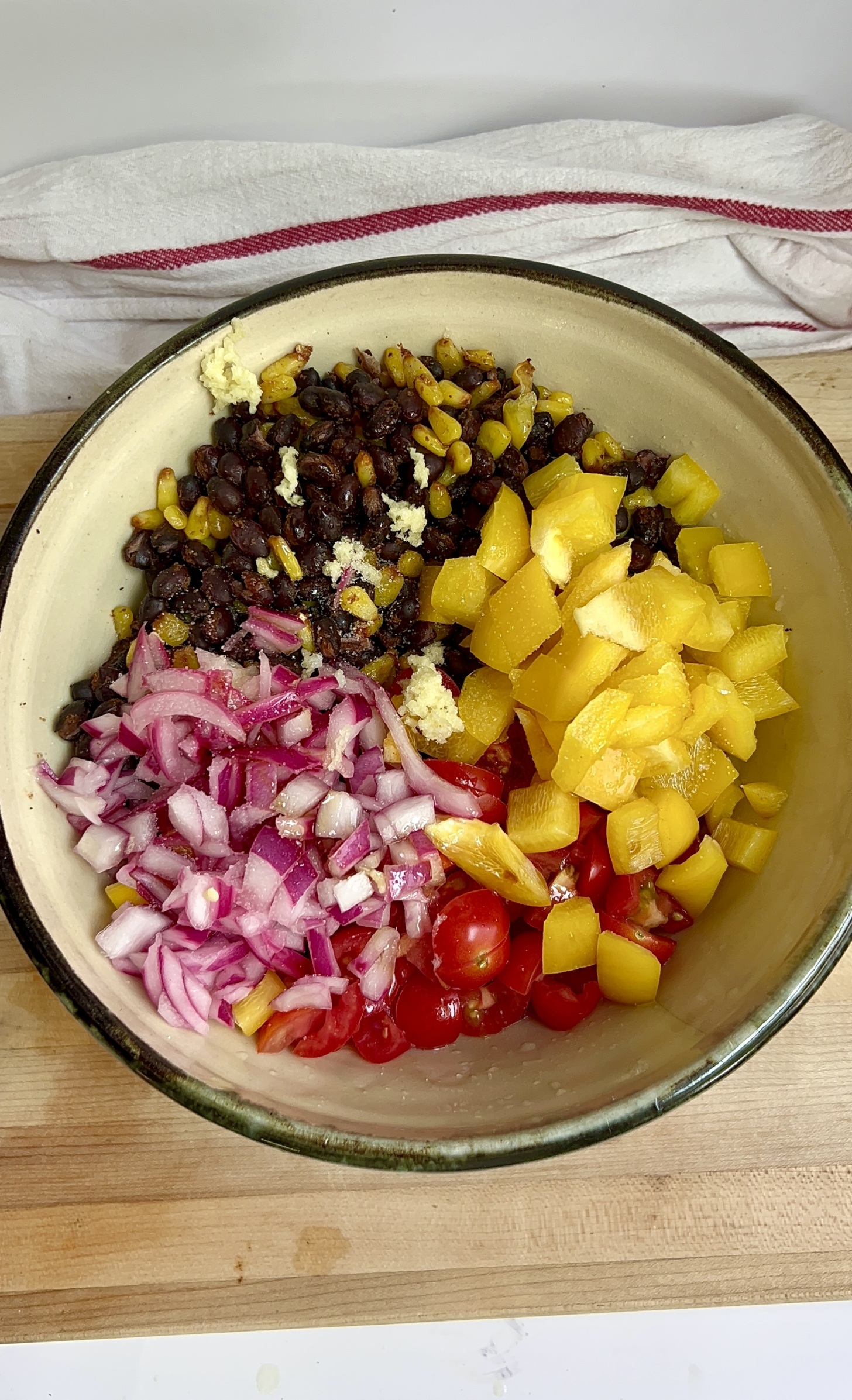Bowl with pickled red onion, bell peppers, black beans and corn inside.