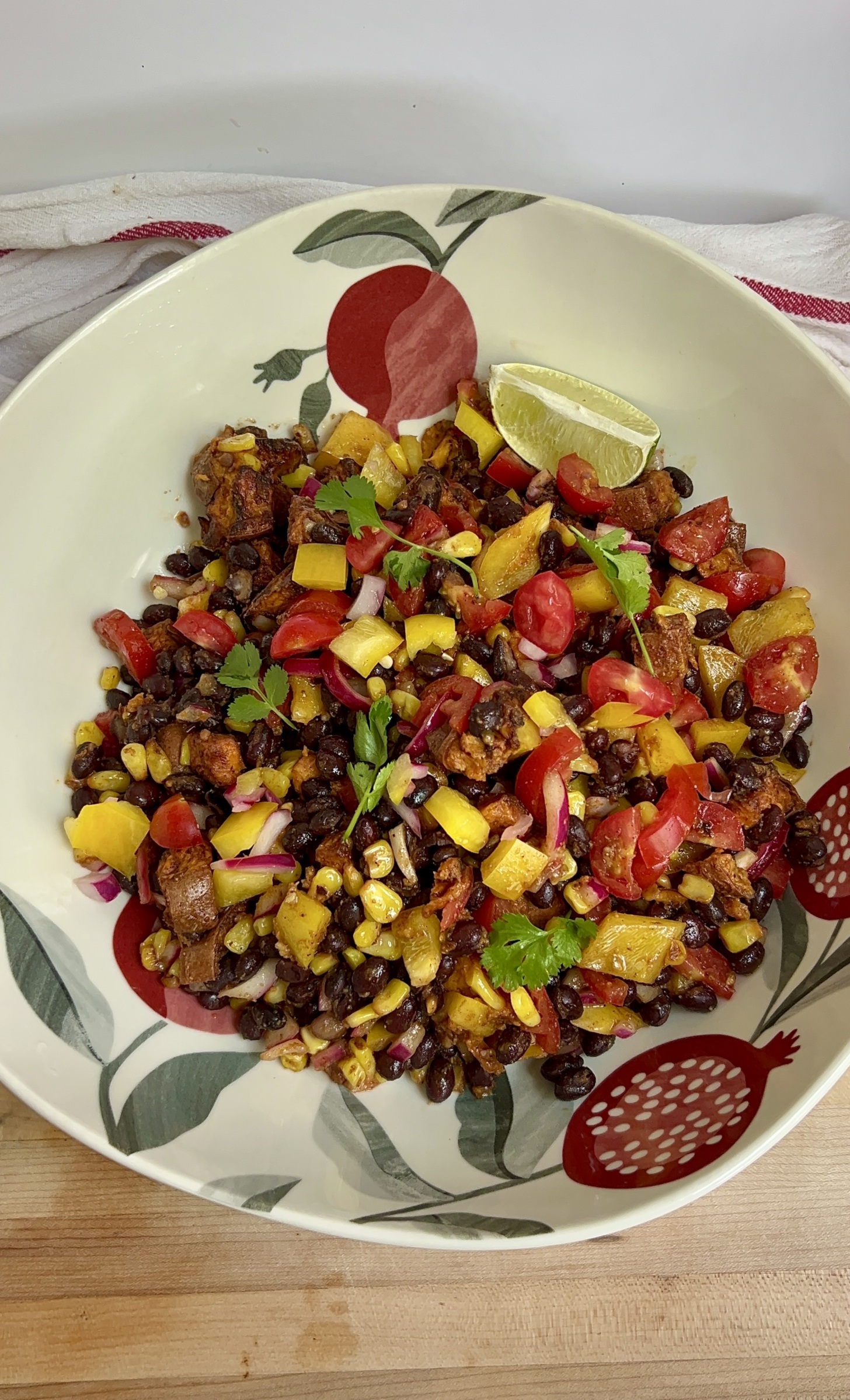 Large bowl with a mixture of peppers, black beans, sweet potato, corn all mixed together.