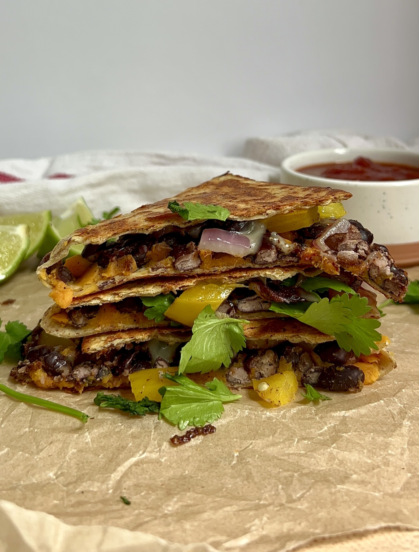 Quesadilla stacked on parchment paper with salsa