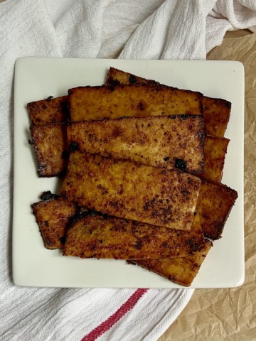 White plate with strips of tofu bacon on top.