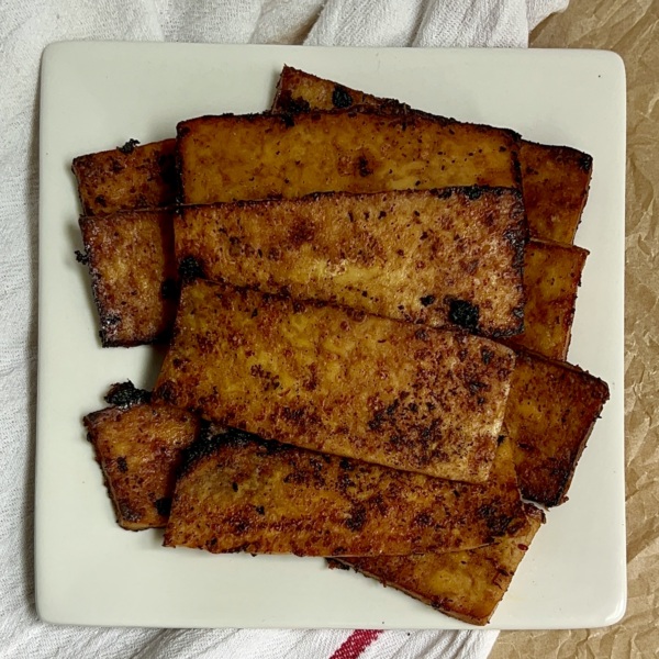 White plate with strips of tofu bacon on top.