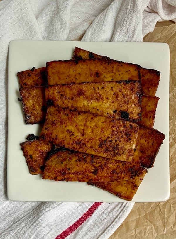 White plate with strips of tofu bacon on top.