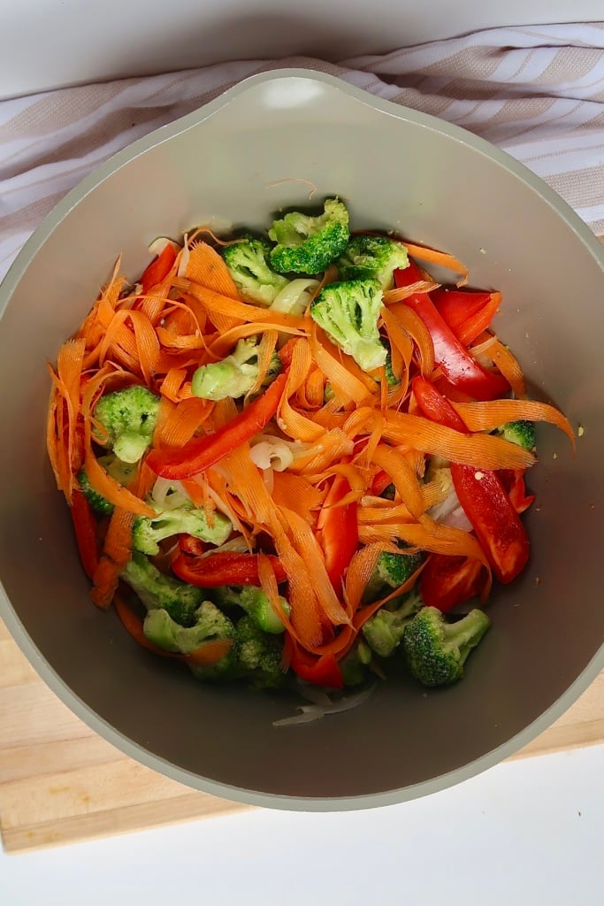 Large pot with sliced carrot, bell pepper and broccoli inside.