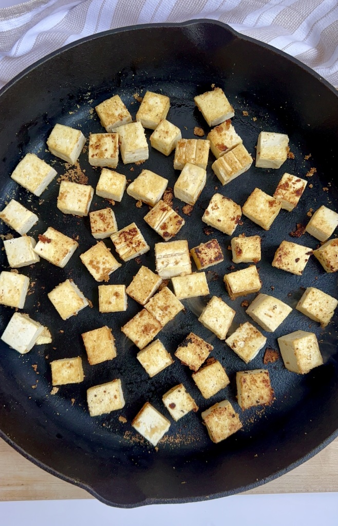 Cubed tofu in a pan that's crispy on the sides.