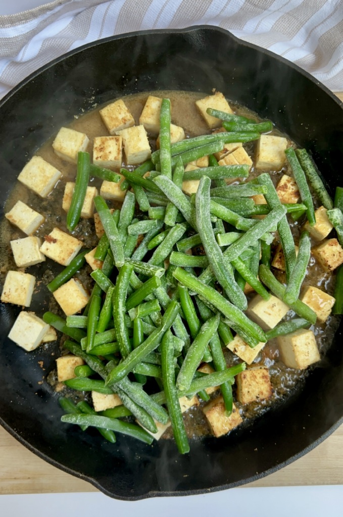 Pan with cubed tofu in it and green beans on top