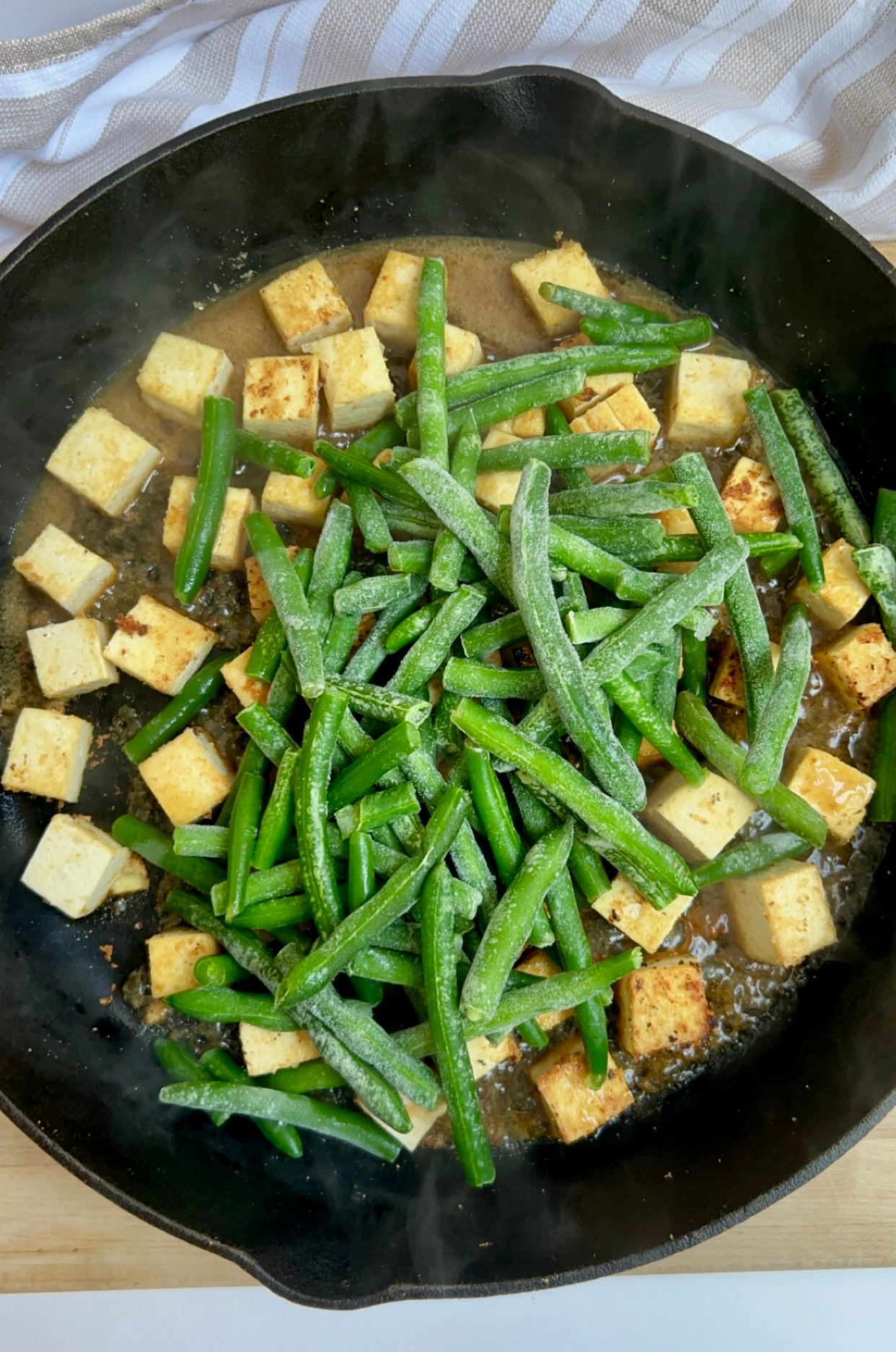 Pan with cubed tofu in it and green beans on top
