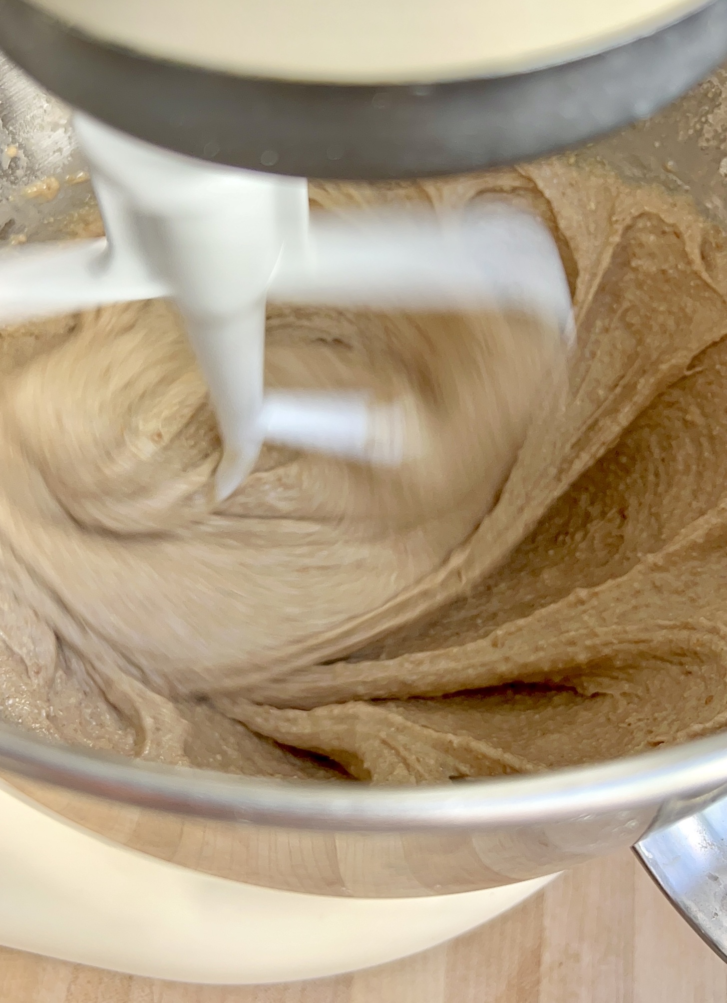 Mixing bowl with muffin batter inside and a whisk mixing it around.