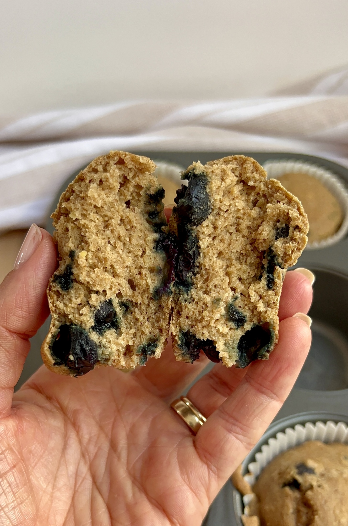 Hand holding blueberry muffin that's broken open.