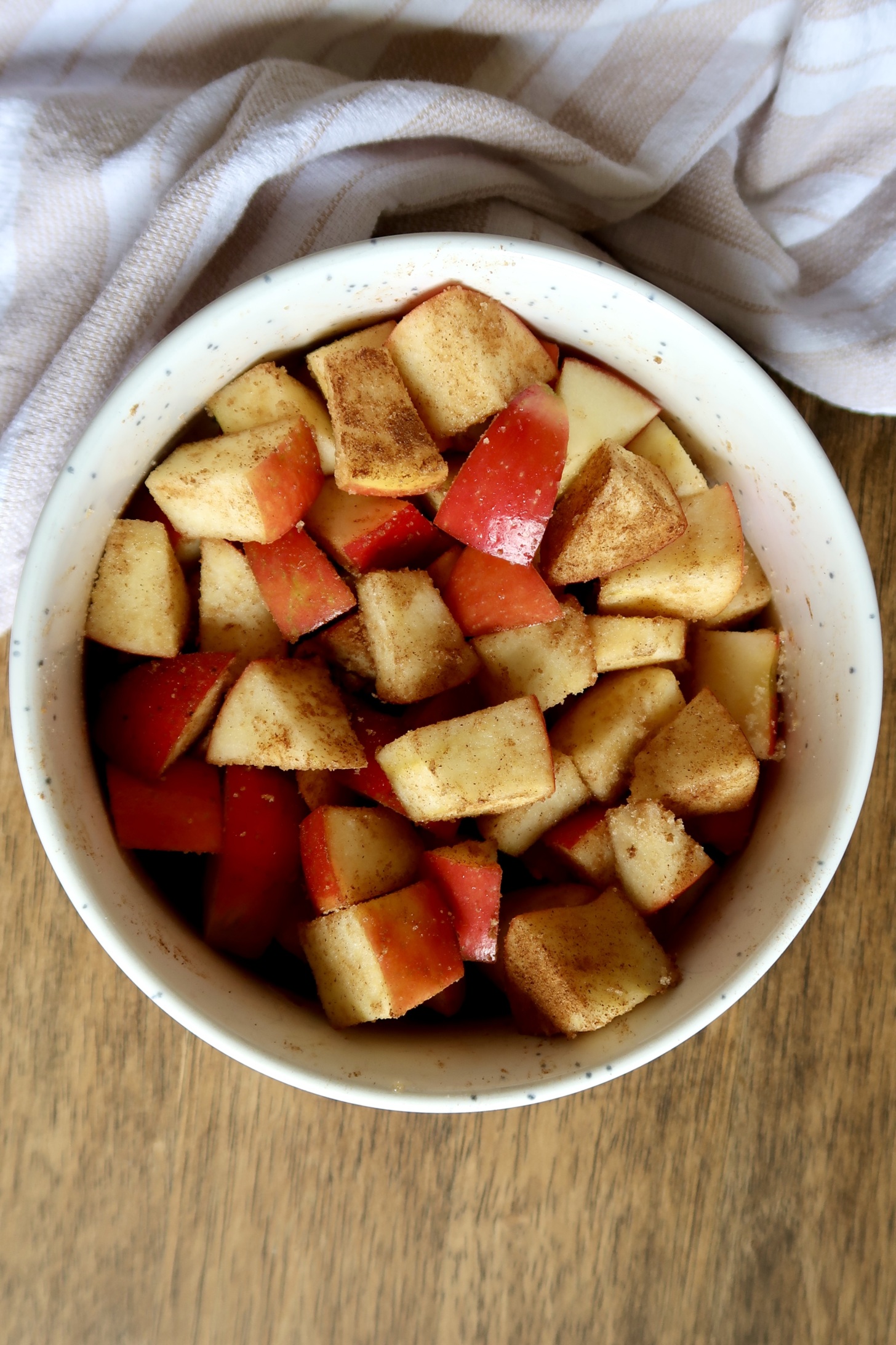 White bowl with diced apple inside covered in cinnamon