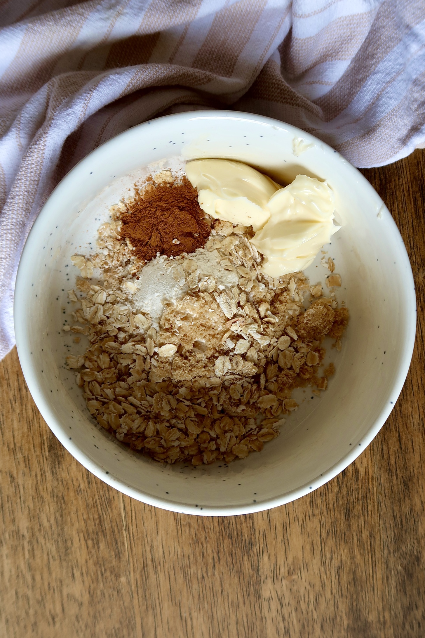 White bowl with oats, cinnamon, brown sugar and butter inside.