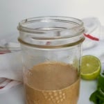 Jar with tahini dressing inside that's orange coloured.