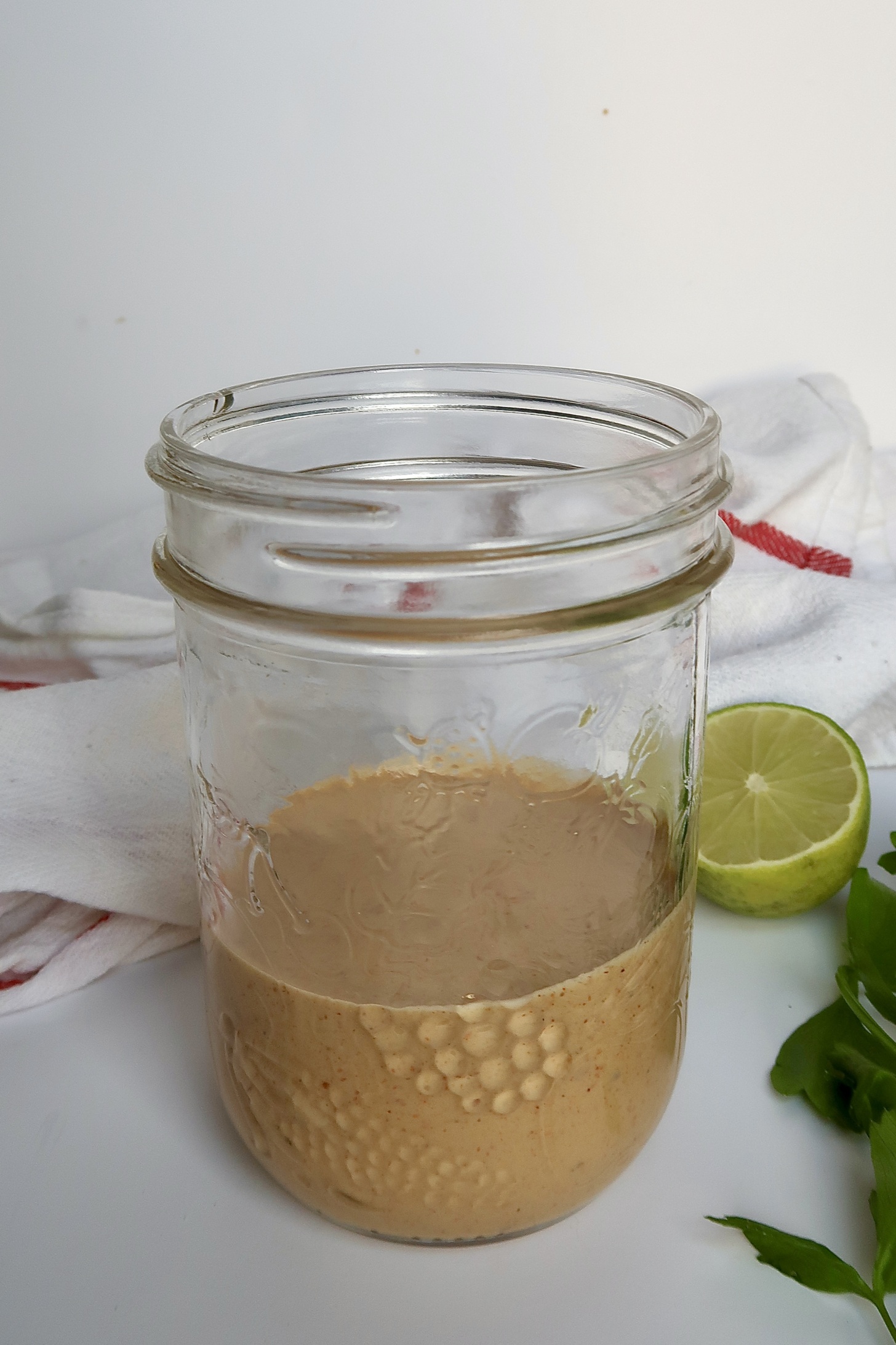 Jar with tahini dressing inside that's orange coloured.