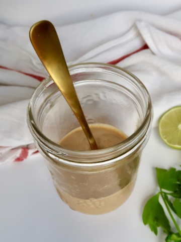 Jar with tahini sauce inside with a spoon