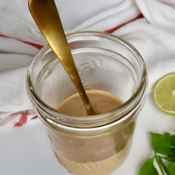 Jar with tahini sauce inside with a spoon