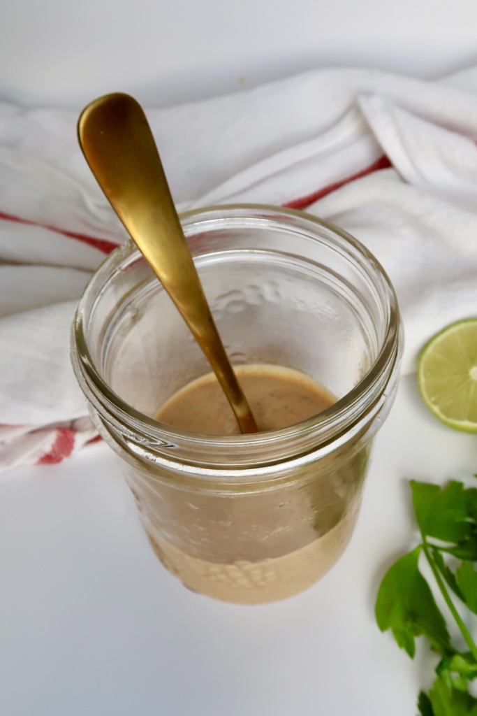 Jar with tahini sauce inside with a spoon