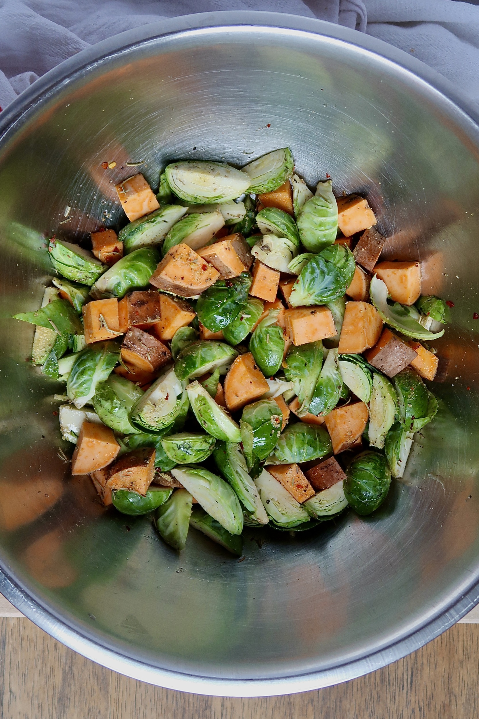 Silver bowl with dived brussel sprouts and sweet potato with oil and spices