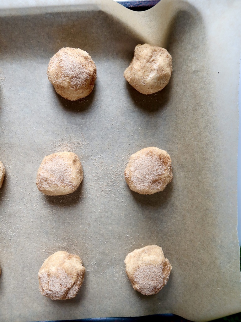 Cookie dough dipped in cinnamon sugar placed on a pan.