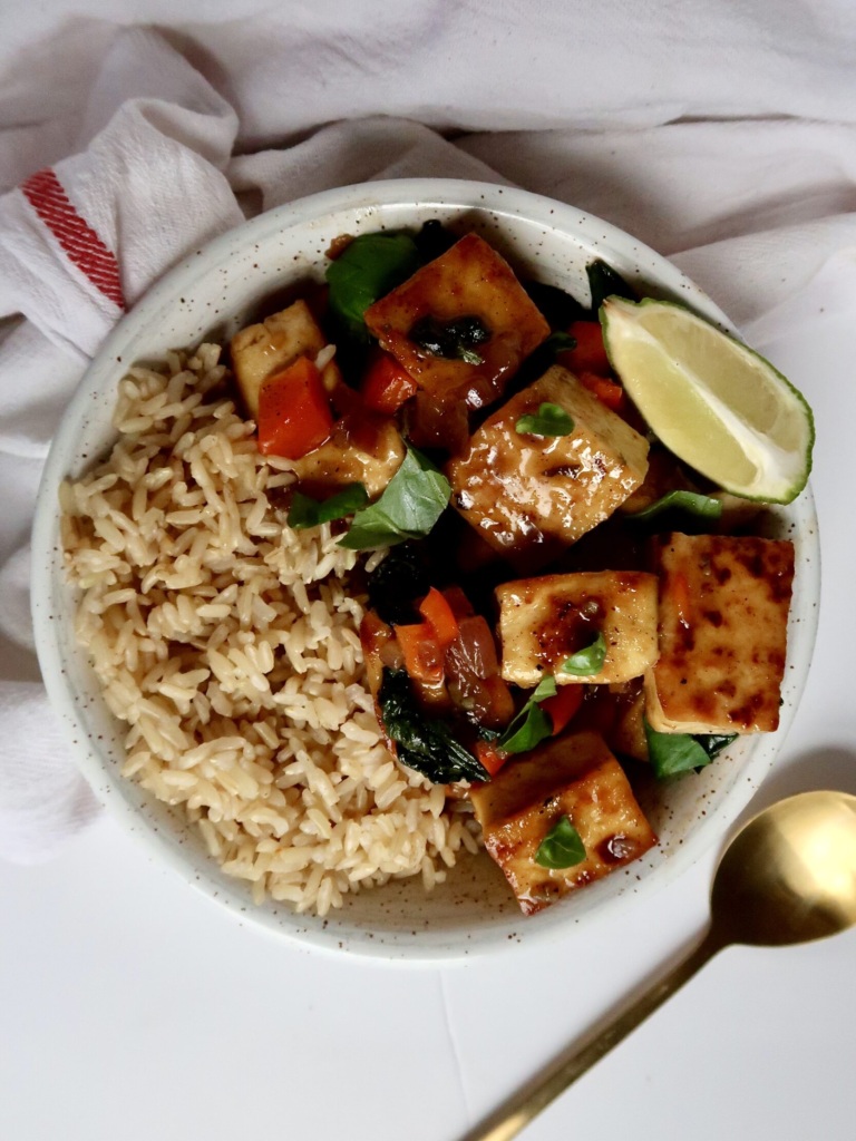 Cubed basil tofu in a bowl with brown rice on the side and a lime wedge.