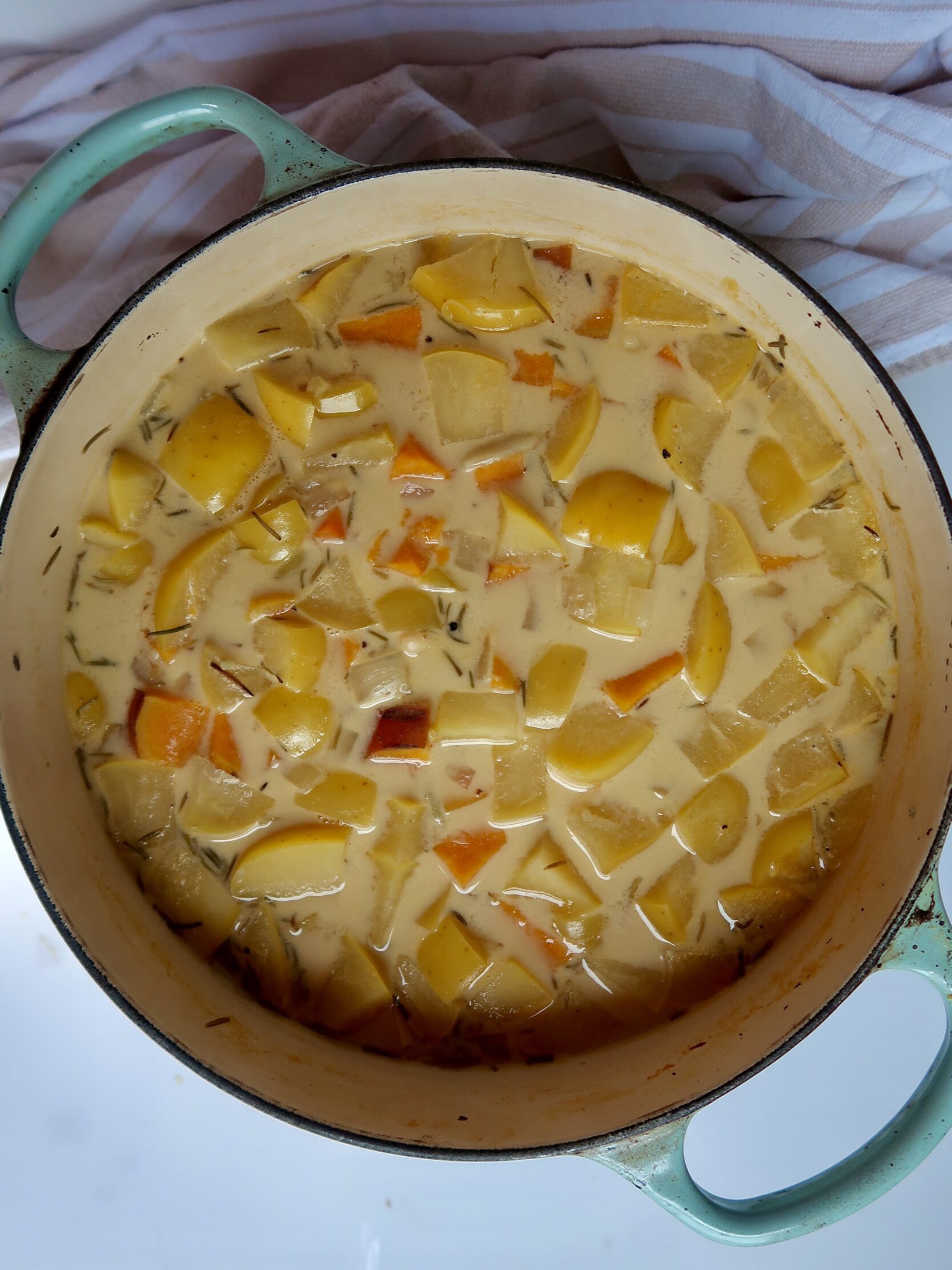 Large pot with chopped sweet potato and apples inside and coconut milk as well.