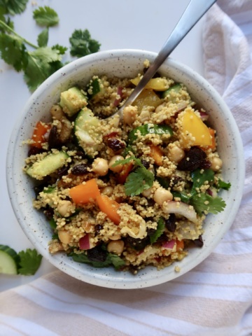 White bowl with couscous, cucumber, bell pepper and chickpeas all mixed together.