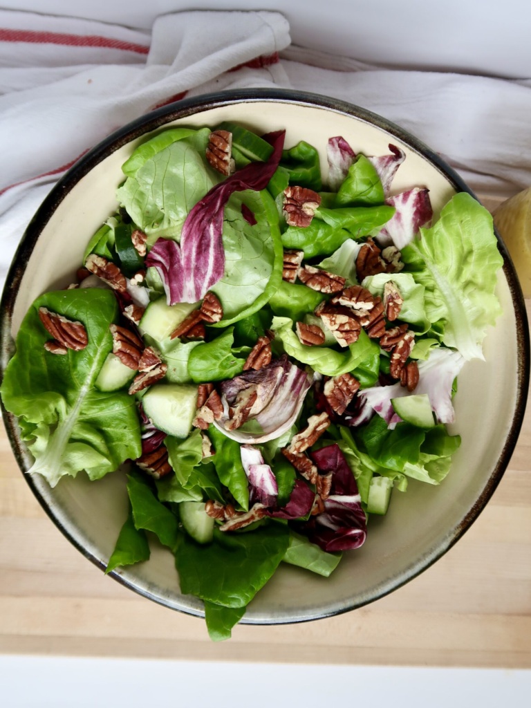 Bowl with greens, radicchio and pecans on top.