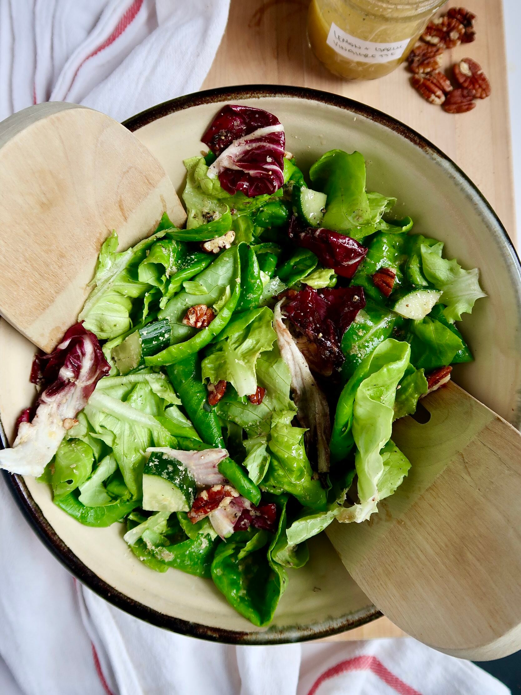 Green and radicchio salad in a bowl with tongs inside.