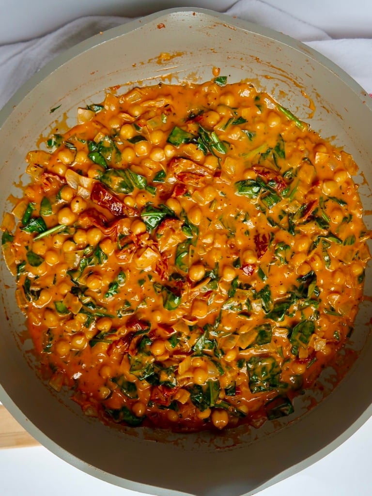 Pan with chickpeas mixed with tomato paste and coconut milk, sundried tomatoes and wilted spinach.