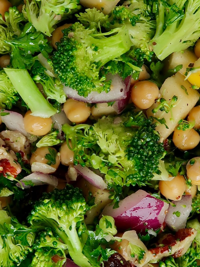 Close up of broccoli, chickpeas, red onion, apples.