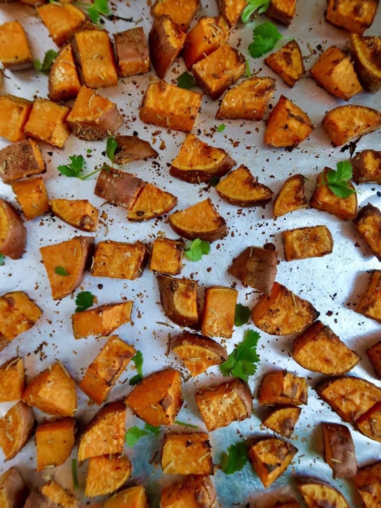 Roasted sweet potato with spices on a sheet pan with cilantro for garnish.