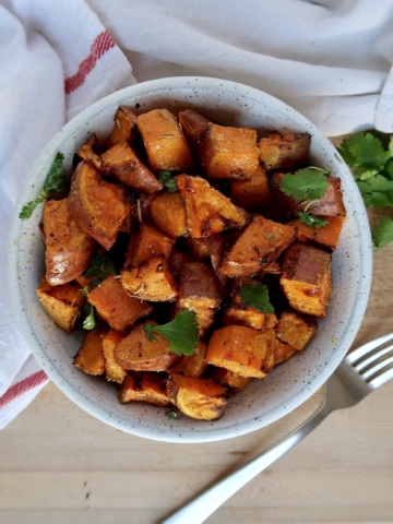 Roasted sweet potato with spices in a bowl with cilantro for garnish.