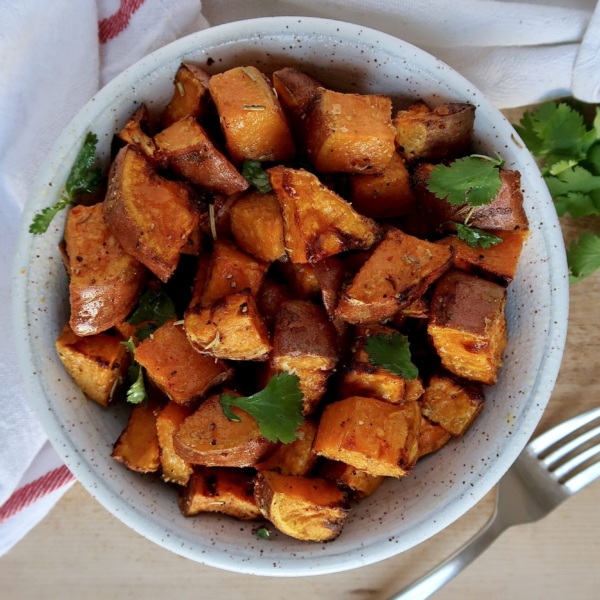 Roasted sweet potato with spices in a bowl with cilantro for garnish.