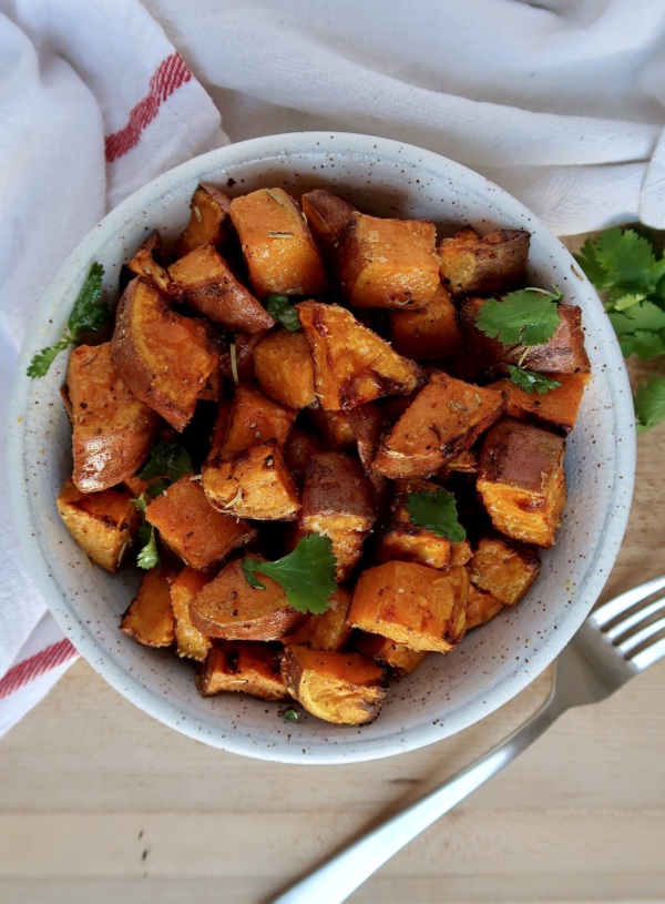 Roasted sweet potato with spices in a bowl with cilantro for garnish.