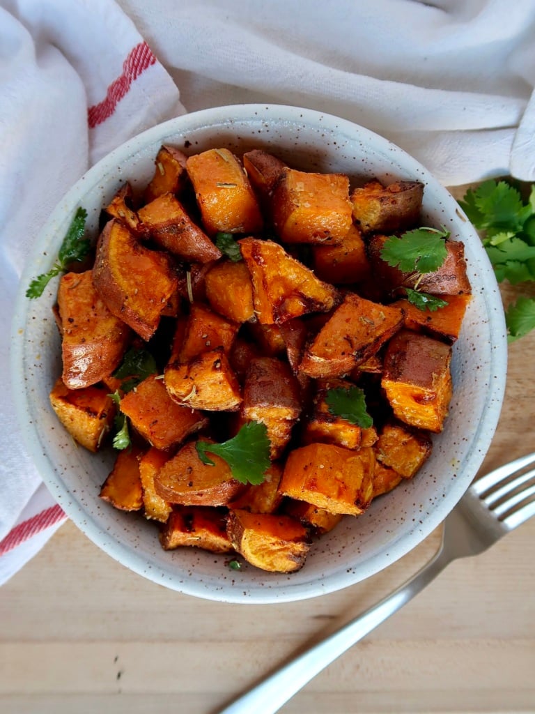 Roasted sweet potato with spices in a bowl with cilantro for garnish.