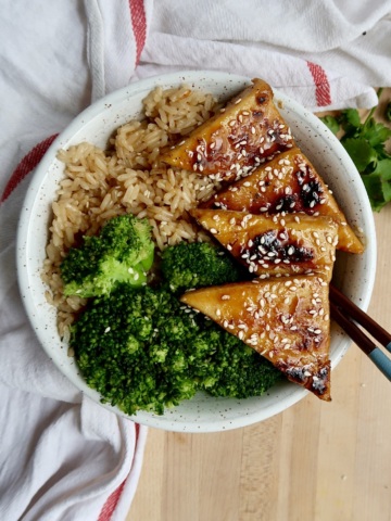 Brown rice, broccoli and maple glazed tofu in a bowl with sesame seeds on top.
