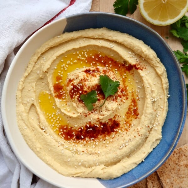 Bowl of hummus garnished with olive oil, paprika, and parsley.