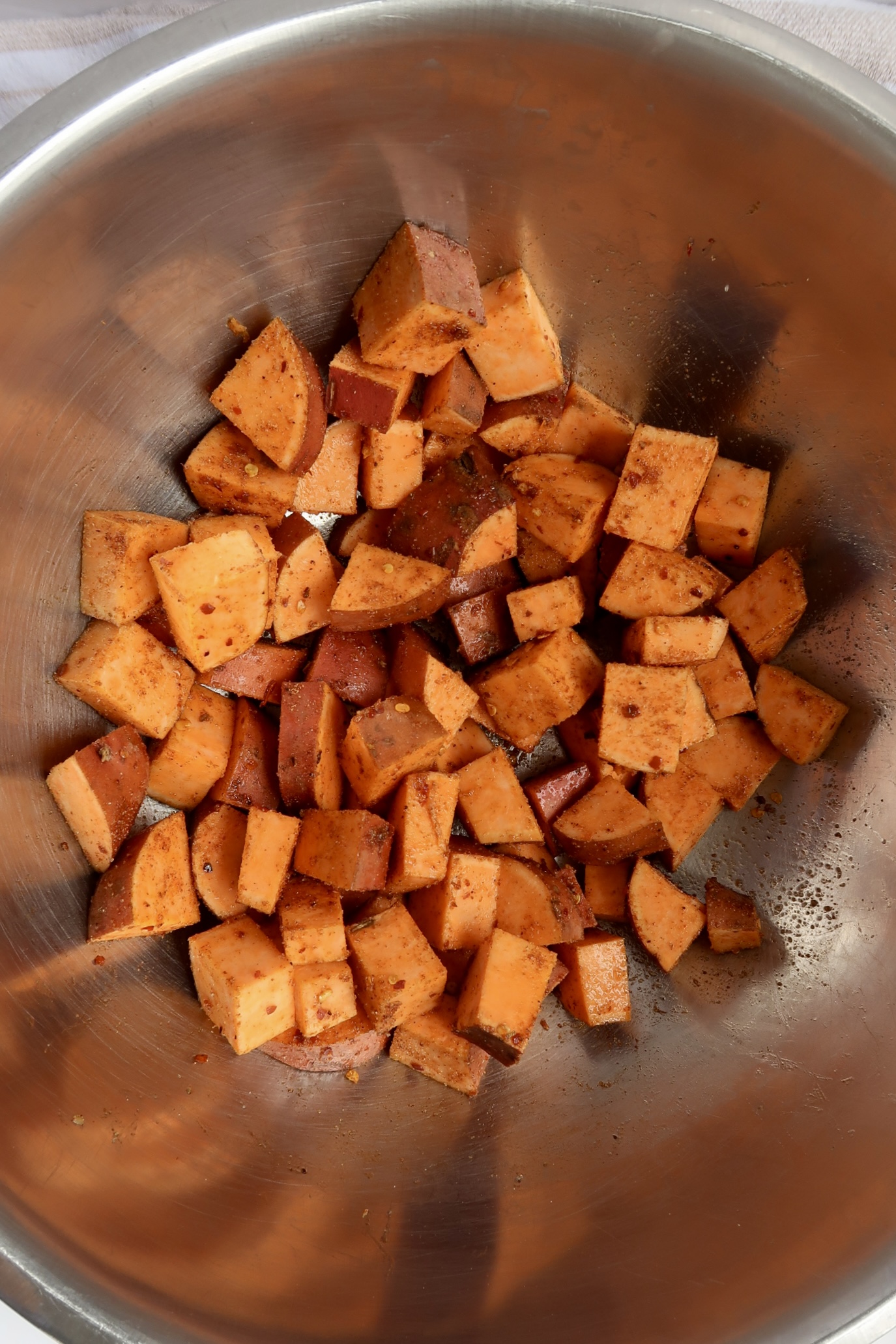 Bowl with diced sweet potato and seasoning on it.