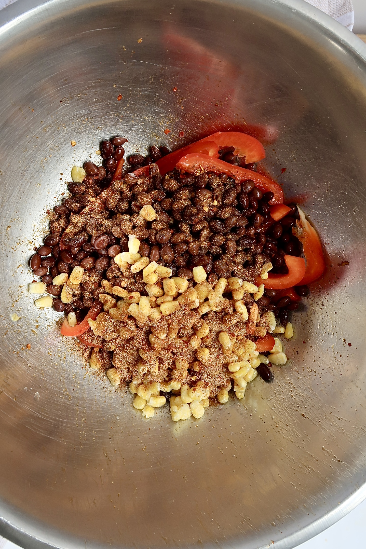 Bowl with black beans, red bell pepper, corn and seasonings.