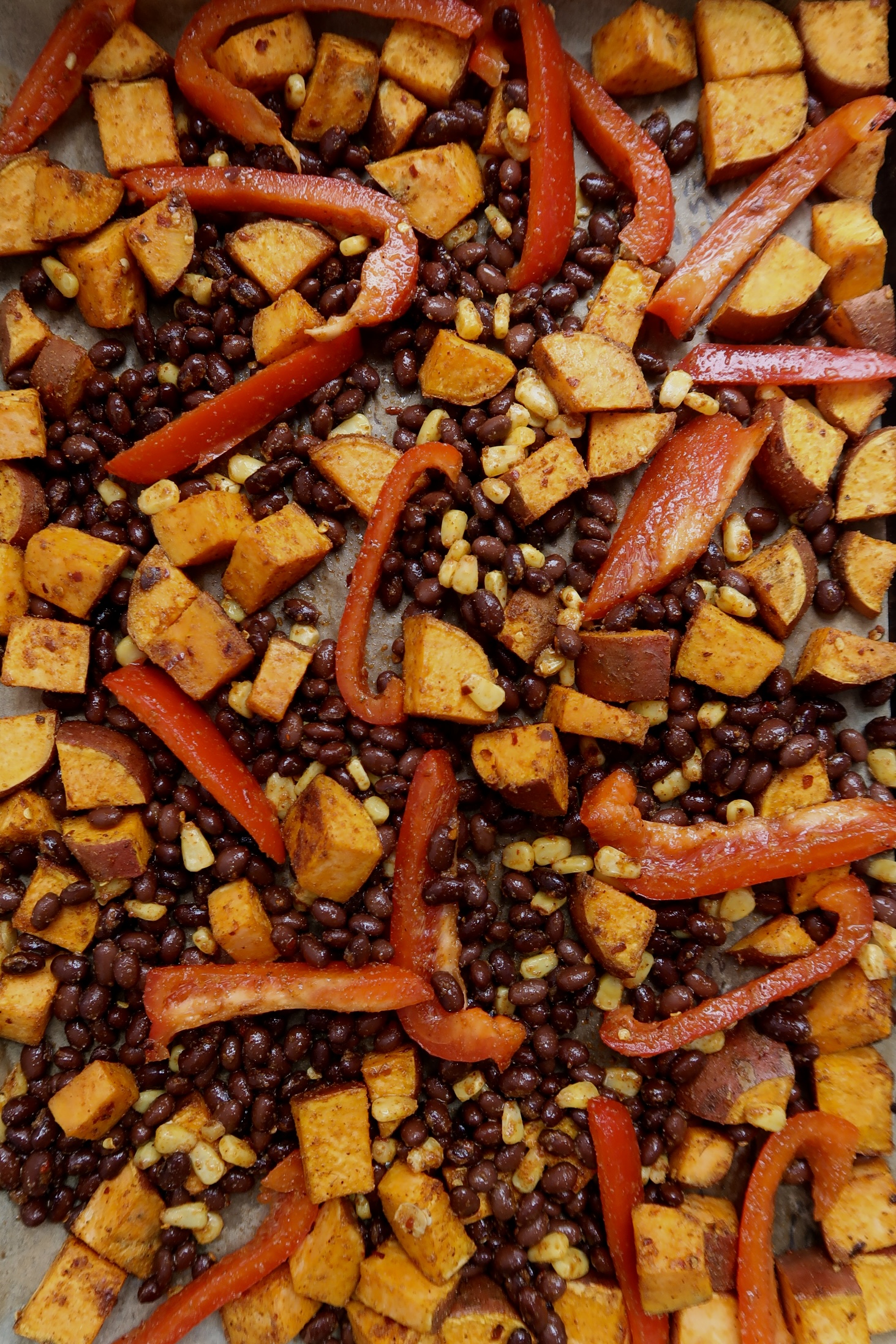 Sheet pan with roasted sweet potato, black beans, bell pepper and corn.