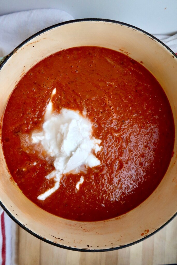 Large pot of tomato soup with coconut milk inside.