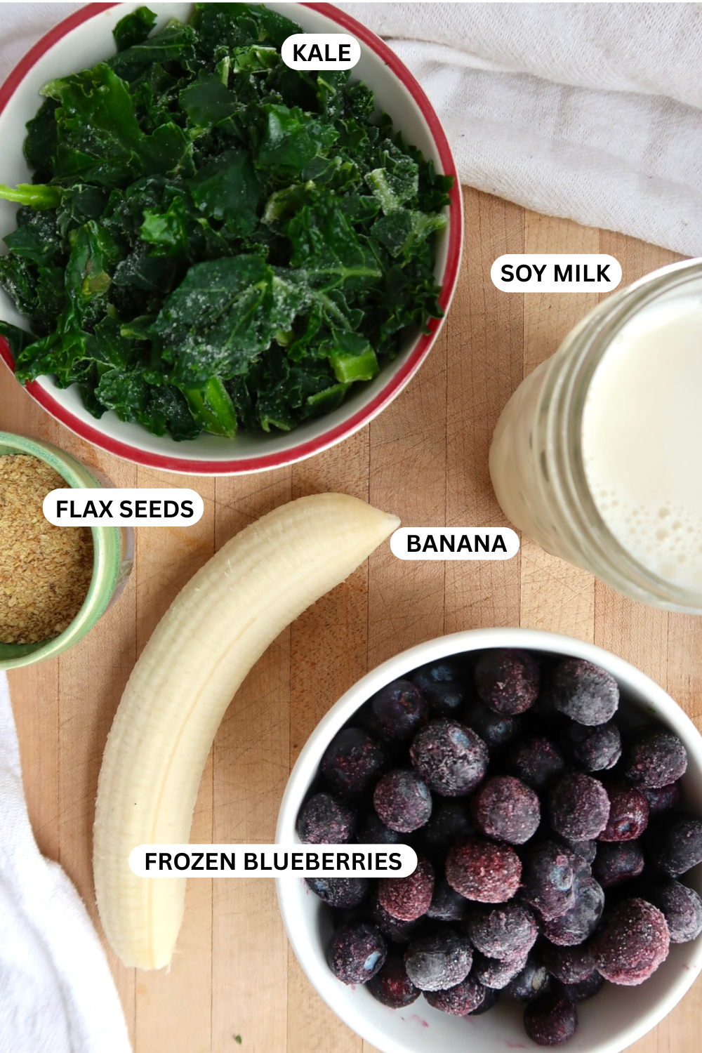 Flatlay of kale, banana, flax, blueberries and soy milk.