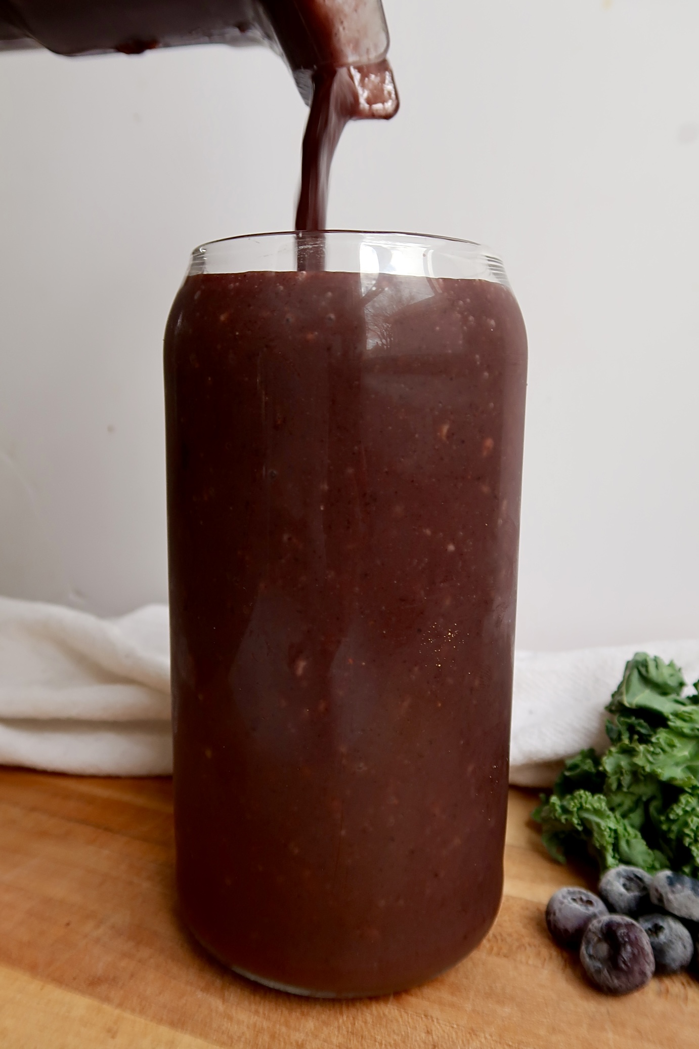 Blueberry smoothie being poured into a glass.