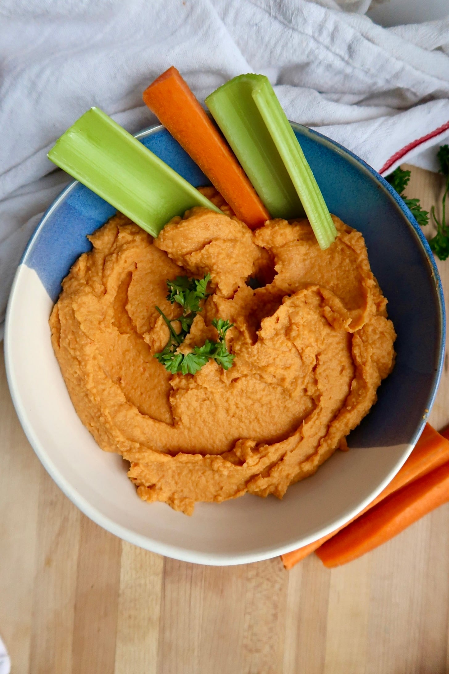 Bowl of buffalo chickpea dip with carrot and celery inside.