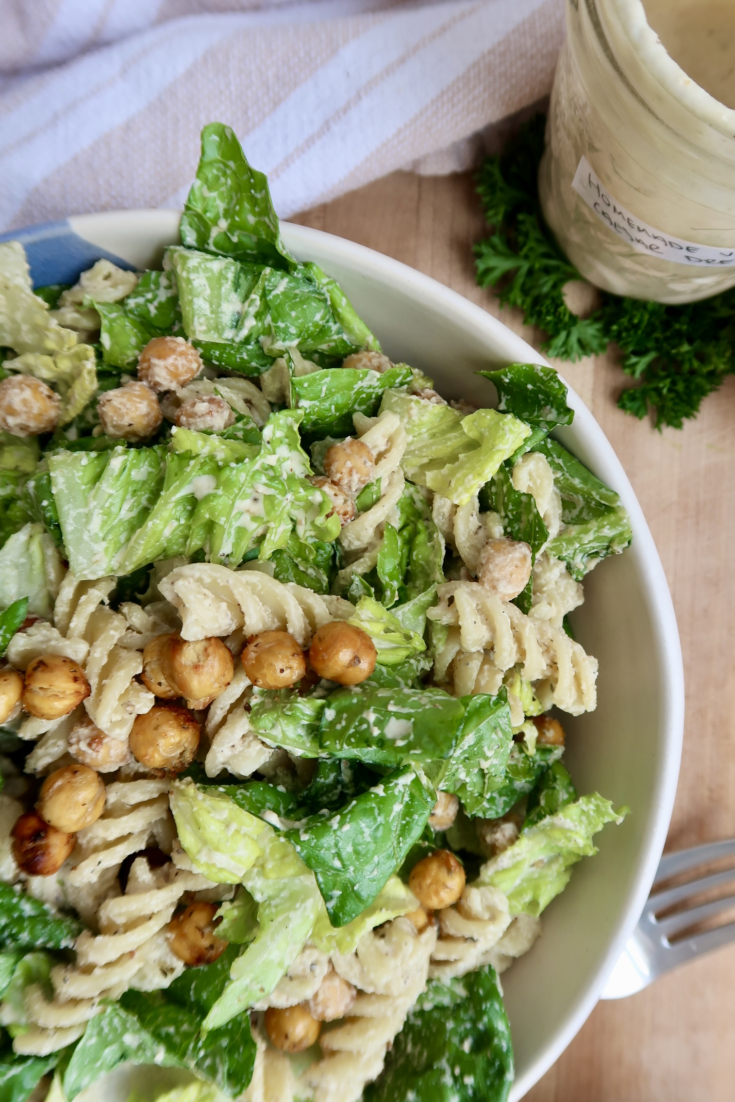Close up of vegan caesar pasta salad with caesar salad dressing on the side.