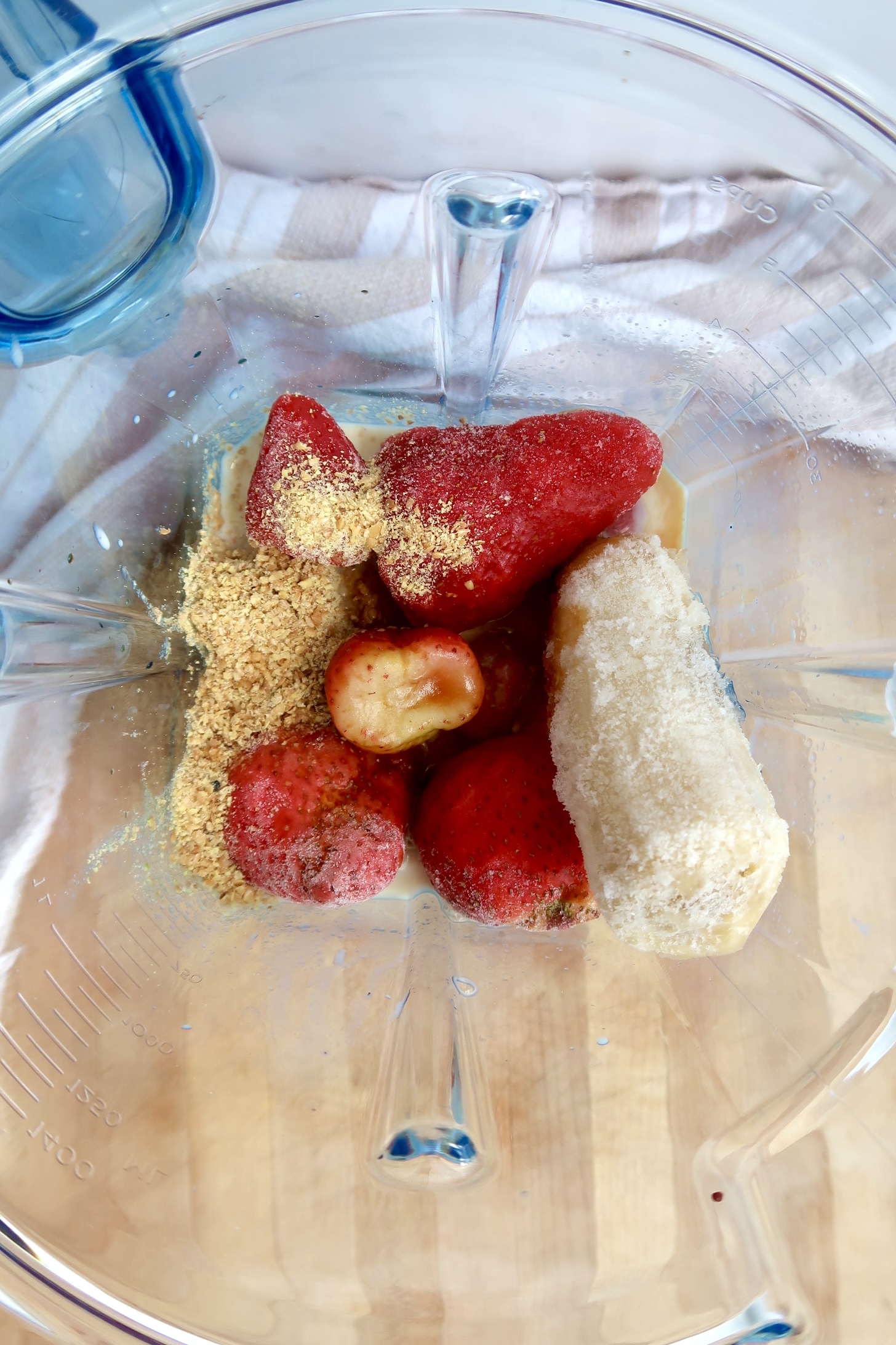 Overhead shot of smoothie container with strawberries, flax and banana.