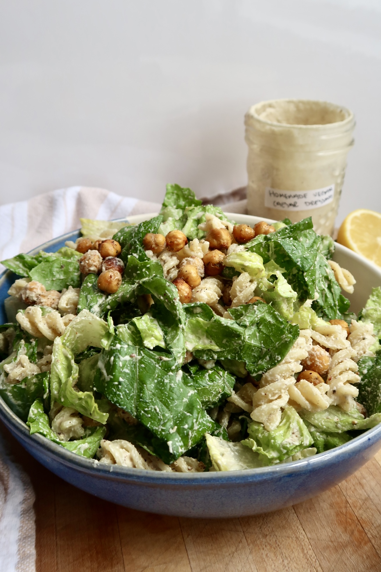 Vegan caesar pasta salad with vegan caesar salad dressing jar in the background.