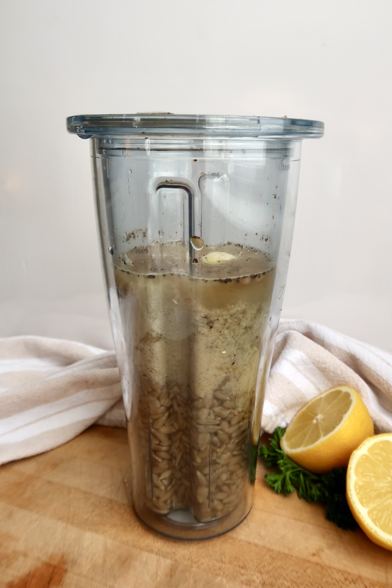Blender container with sunflower seeds, water, nutritional yeast, pepper and garlic.