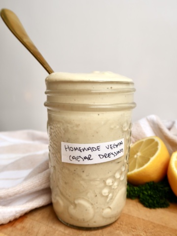 Jar labeled homemade vegan caesar dressing with caesar dressing inside and a spoon.