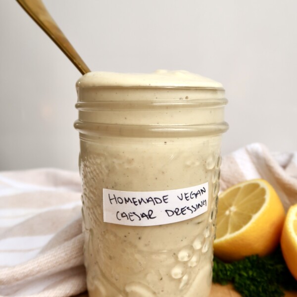 Jar labeled homemade vegan caesar dressing with caesar dressing inside and a spoon.